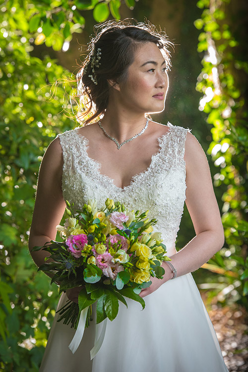 bride with bouquet backlit in beautiful garden