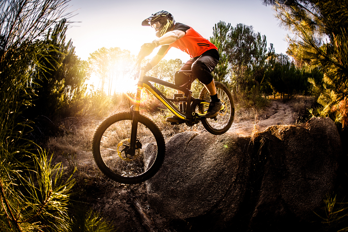 mountainbiker jumping off a rock downhill as sun sets