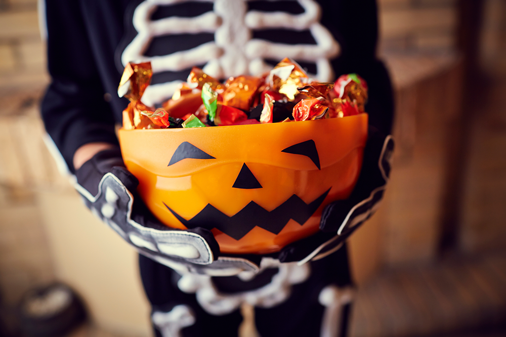 an orange bowl of halloween candy is held by a child