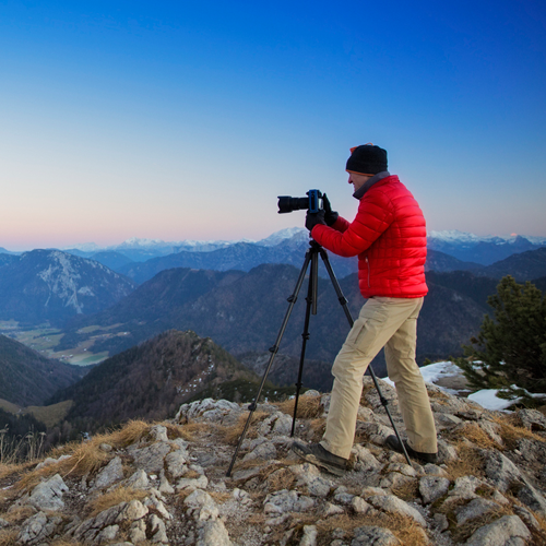 Photographer stood on mountain with a mounted tripod