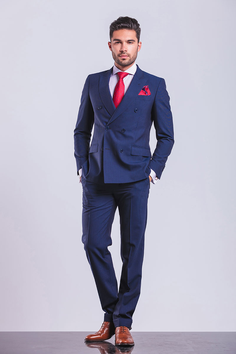 male model in bright blue suit with red tie poses for camera with hands in pckets